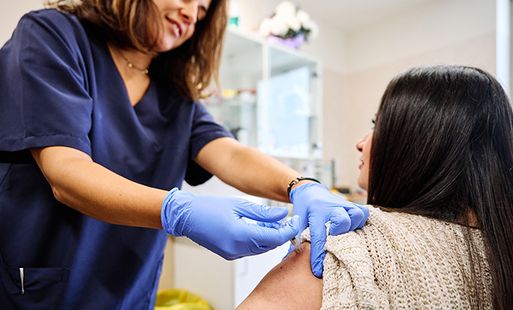 A nurse providing a vaccine to a female patient