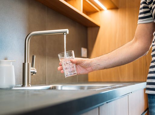 A person getting a glass of water from a kitchen tap.