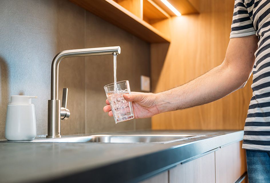 A person getting a glass of water from a kitchen tap.