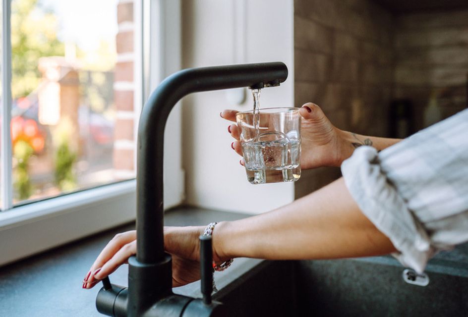 Someone filling up a glass of water from a kitchen tap.