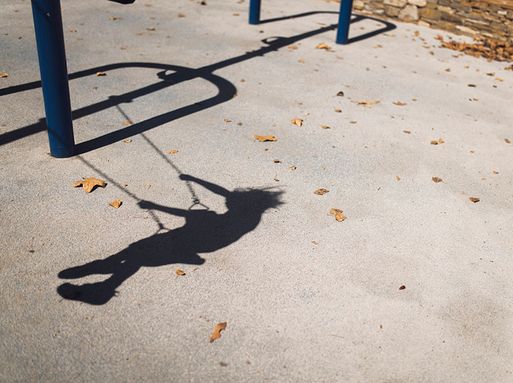 The shadow of a child playing on a swing set