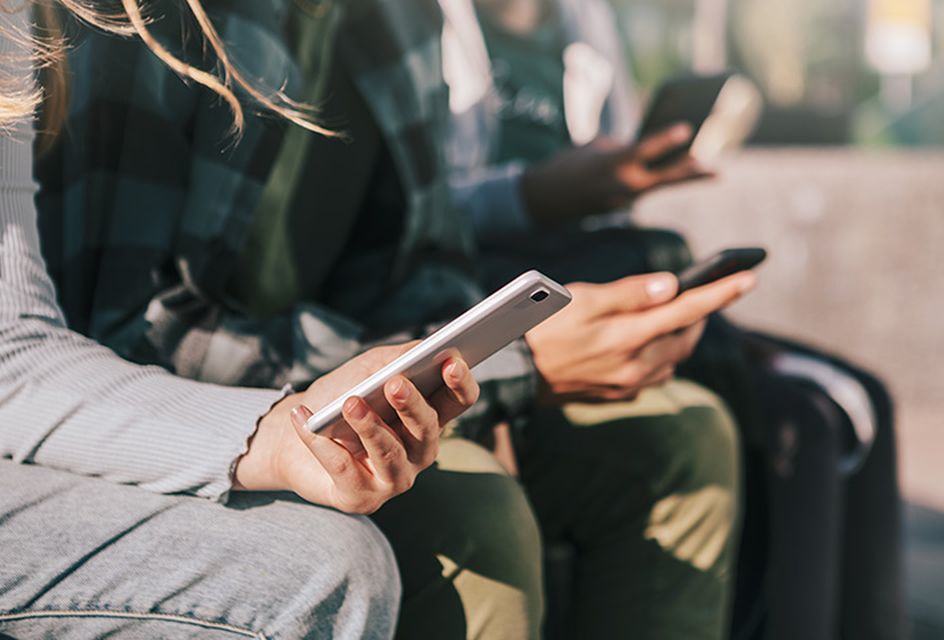 A row of teenagers holding mobile phones