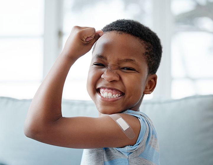 Young boy with plaster on his arm cheering with happiness after getting a vaccination