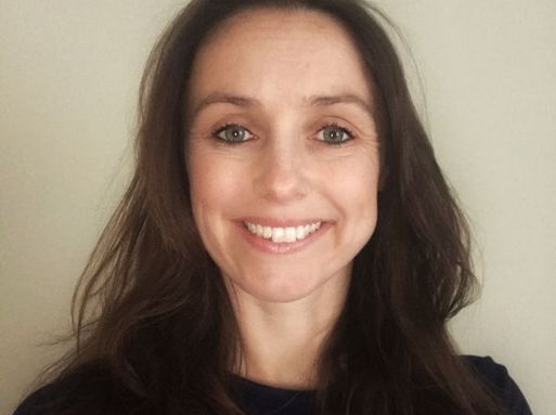 Amy Stevens, a white woman with brown hair and brown eyes smiling