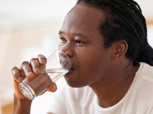 Image of a man drinking a glass of water against a bright background