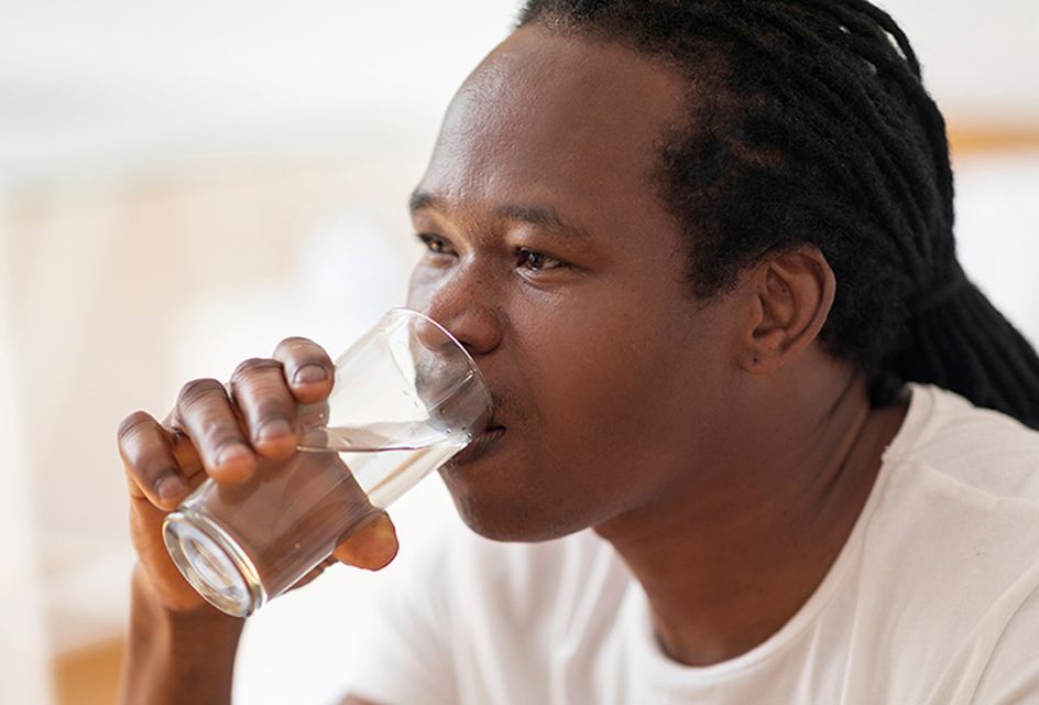 Image of a man drinking a glass of water against a bright background