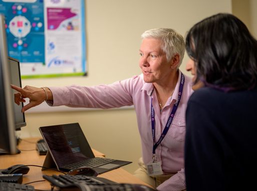 A woman is pointing at a computer screen