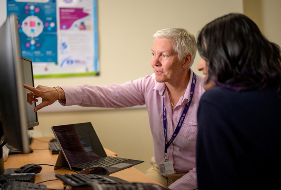 A woman is pointing at a computer screen