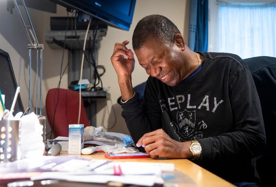 An elderly black mine smiles as he looks at his phone